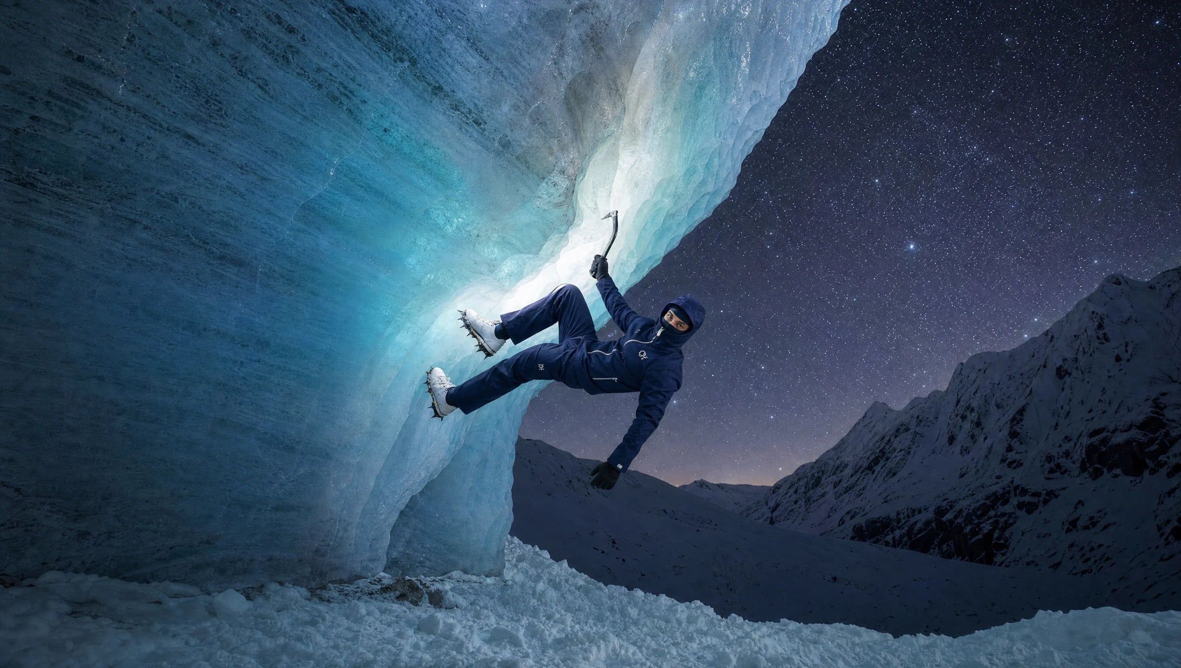 The navy CROWNED HEAVEN Rain Shell worn while ice climbing beneath a starry night sky.
